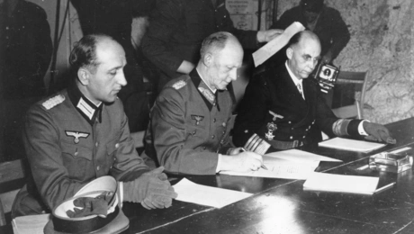 Ο Στρατηγός Άλφρεντ Γιόντλ, στο κέντρο, υπογράφει την άνευ όρων παράδοση όλων των ένοπλων γερμανικών δυνάμεων που επιβλήθηκε από τις Συμμαχικές Δυνάμεις, στο αρχηγείο του Ανώτατου Διοικητή Αϊζενχάουερ στη Ρεμς της Γαλλίας, στις 7 Μαΐου 1945.